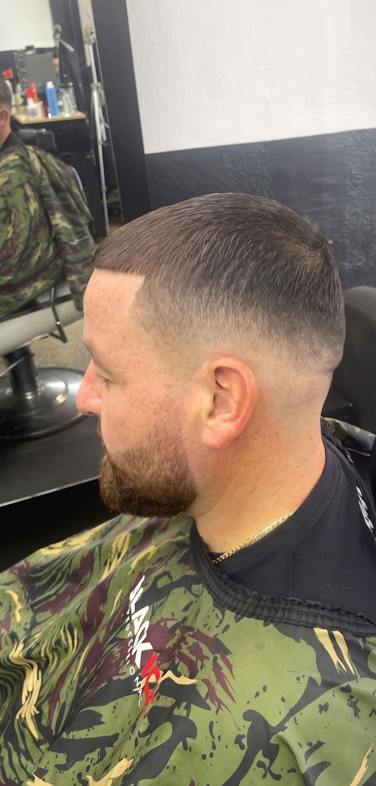 Side profile of a short fade blended into a trimmed beard and a clean cheek line.